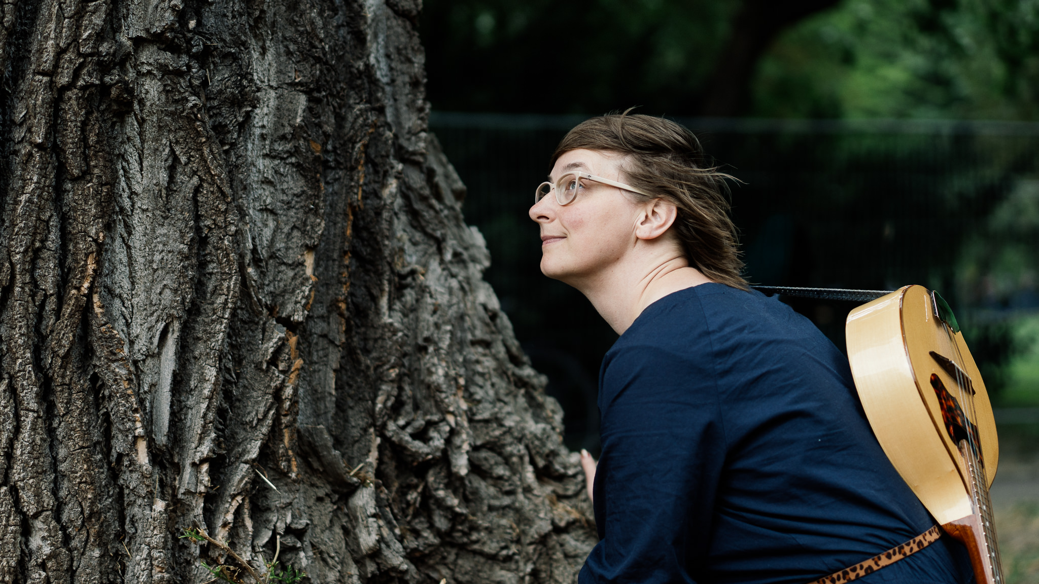 Peggy Luck hockt mit Mandoline vor einem Baum und schaut in den Himmel
